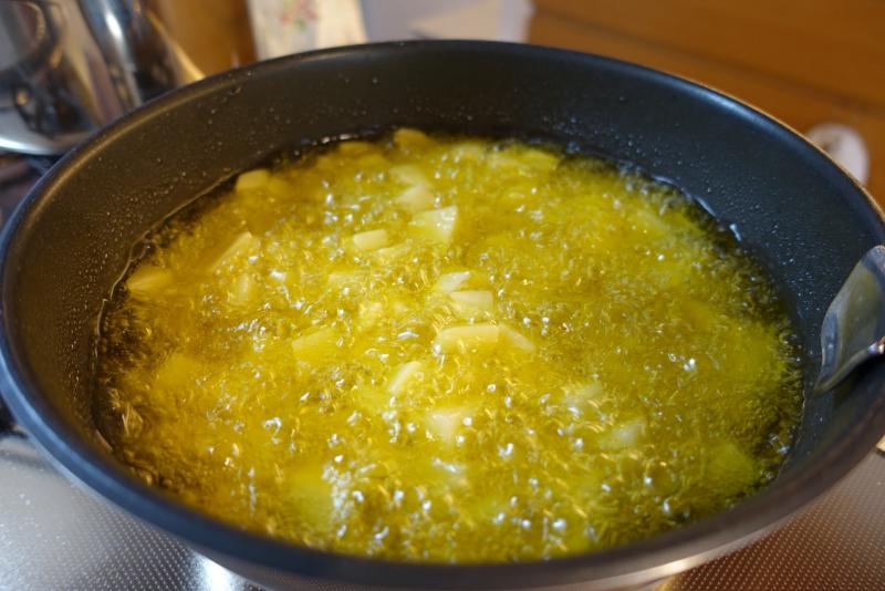 オリーブオイルでサイコロ状に切ったポテトを揚げます